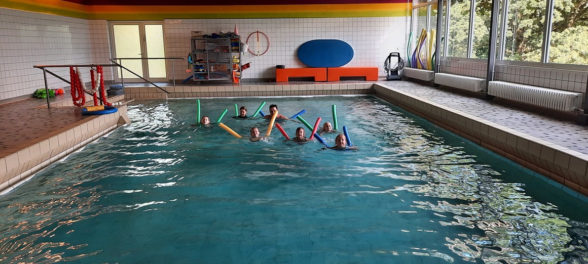 Auf dem Foto sieht man Kinder im Schwimmbad mit Schwimmnudeln